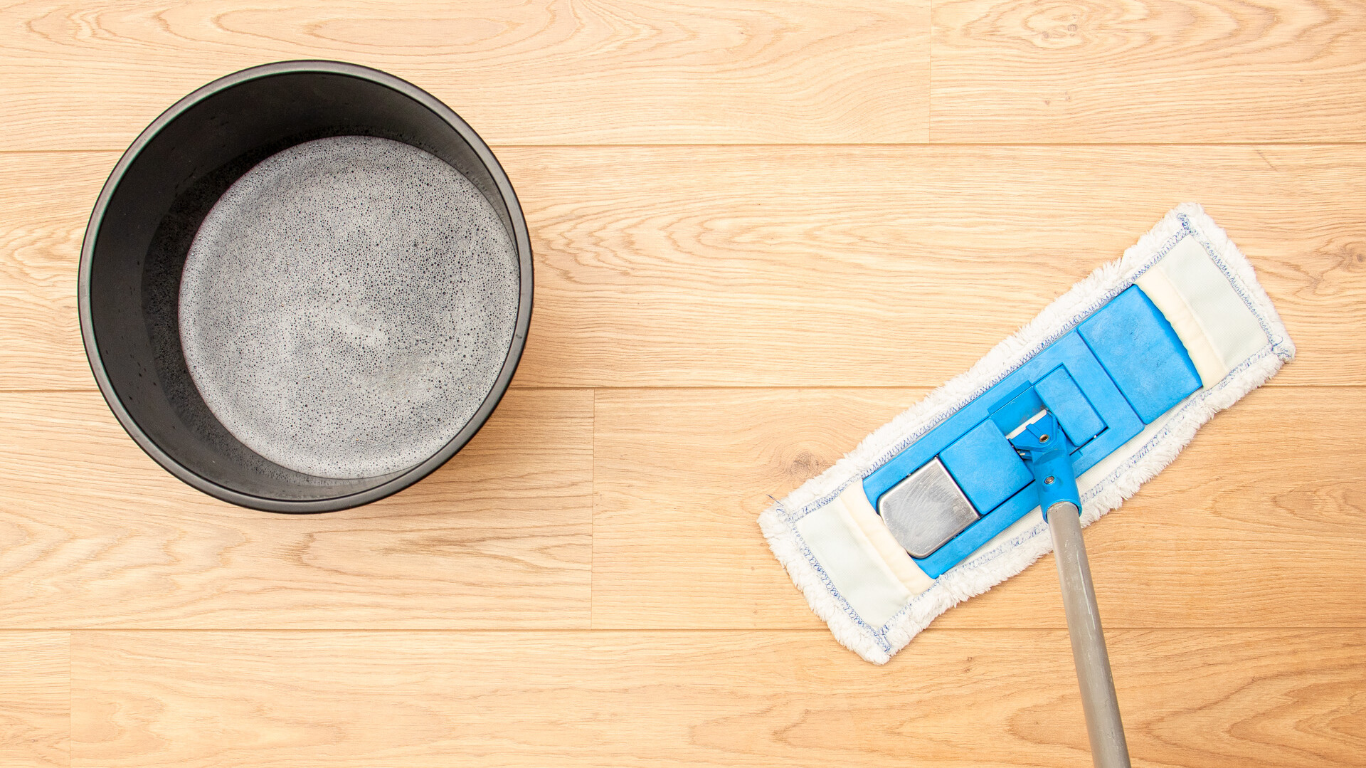 Regelmäßige Reinigung von Parkett und Holzböden: Saugen und nebelfeuchtes Wischen mit den richtigen Reinigungsmitteln Putzeimer und Wischer für die Reinigung eines Holzbodens